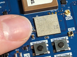Finger pointing at a small rectangular chip (SOC)