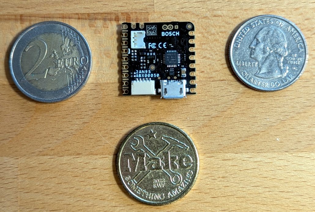 Nicla Sense ME next to three coins, each roughly the same size as the board.