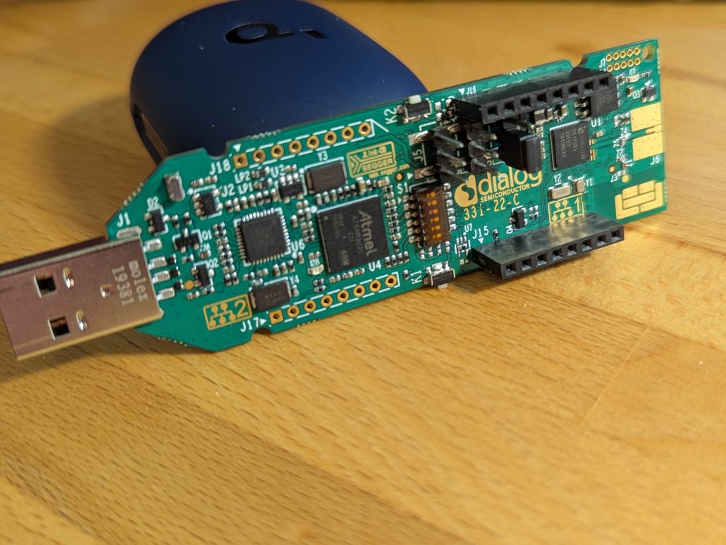 Renesas da14695 propped against a wireless earbud case.