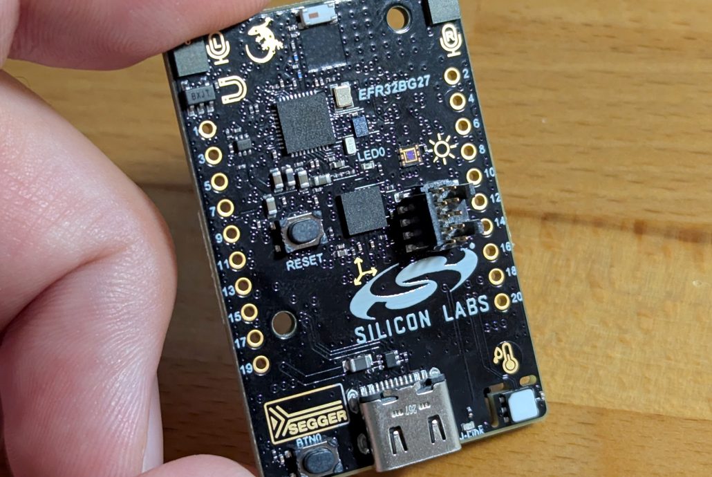 Black rectangular development board about the size of two postage stamps with a white Silicon Labs logo on it.