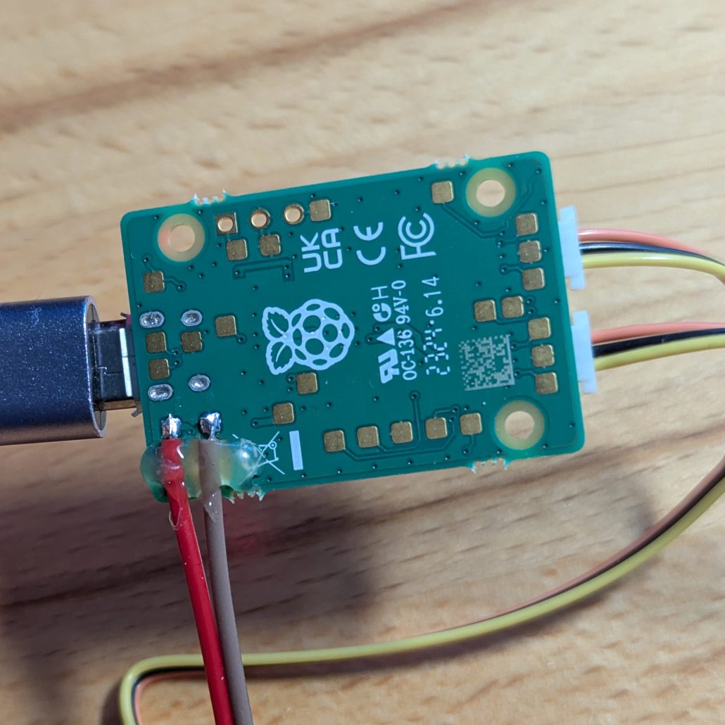 Underside of Raspberry Pi Debug Probe with a number of copper test points and two wires soldered to them
